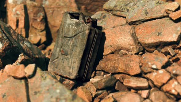 Old Rusty Metal Canister for Gasoline Fuel at Rocks alt