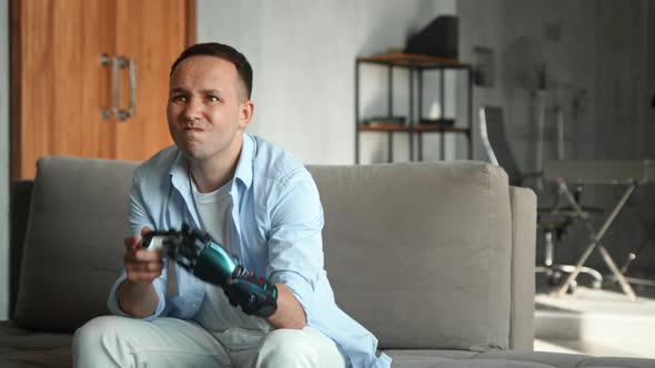 Serious cyborg man with artificial limb hand plays console game round