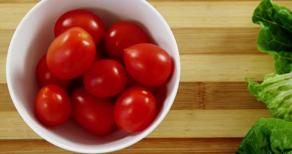 Lettuce and tomatoes in bowl on chopping board