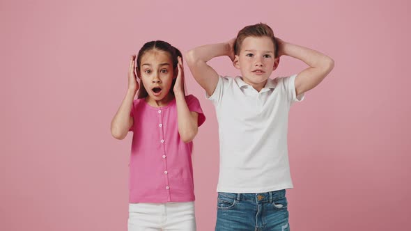 Studio Portrait of Emotional Little Boy and Girl Feeling Excited and Shocked Touching Heads in