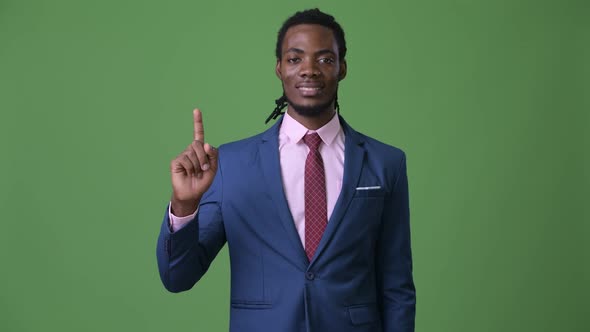 Young Handsome African Businessman with Dreadlocks Against Green Background