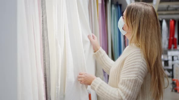 Woman in a Protective Mask Closeup in the Store Chooses Home Textiles Curtains