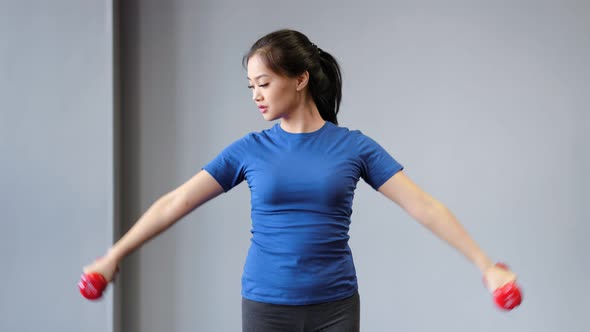 Confident Young Asian Fitness Female Doing Workout Exercise Using Dumbbells Enjoying Training