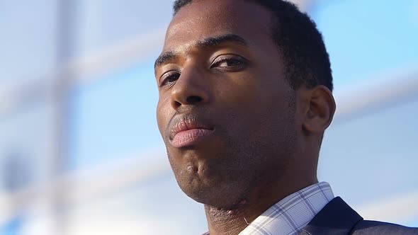 African American Businessman  looking at camera: corporate building background