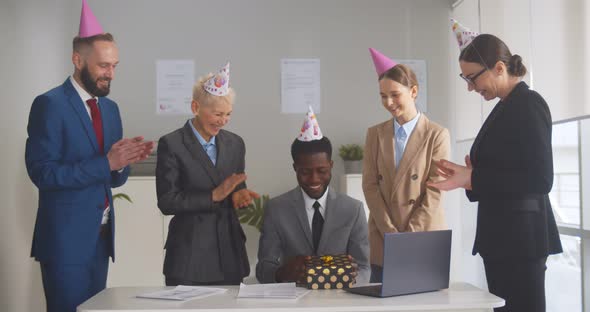 Happy Coworkers Celebrating Afroamerican Man Birthday with Gift and Caps