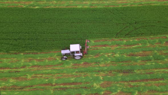 Mowing with a Agriculture Machine Tractor with Mowers on the Big Farm Field