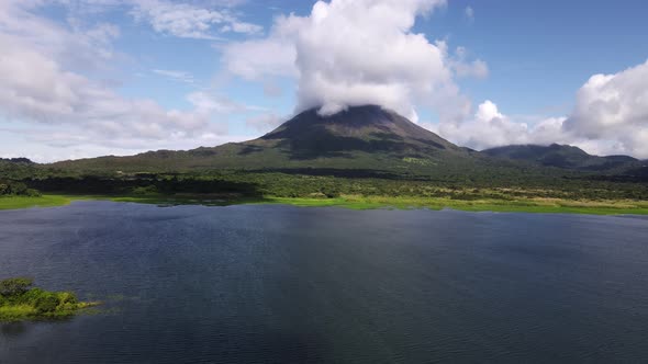 Aerial video approaching famous Arenal Volcano in Costa Rica during wet season. Lush green wetland f