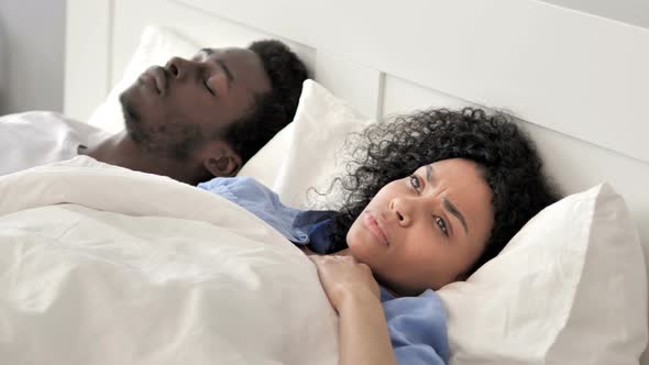 Thinking African Woman Lying in Bed, Sleeping Boyfriend