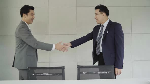 Two asian confident businessman shaking hands during a meeting in the office