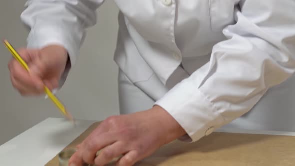 Baker Using a Pencil and a Small Metal Cylinder to Make Circular Shapes on Parchment Paper to Aid in