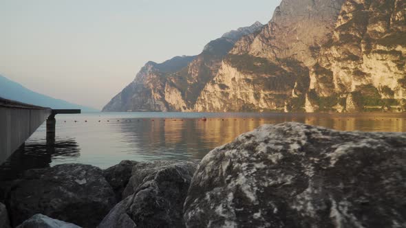 Riva del Garda beach with Garda lake at sunrise. Shooting between rocks in 4k