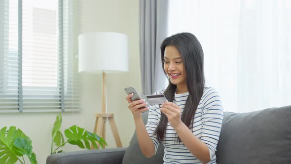 Asian attractive woman enjoy shopping online in living room at home.