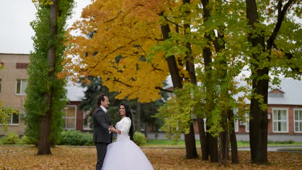 Romantic Wedding in Park in Autumn Day Bride in White and Groom in Black are Dancing Outdoors