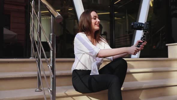 Blogging. Woman with camera recording video on street