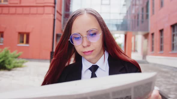 Thoughtful Young Woman Reading Newspaper on Street