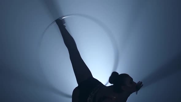 Gymnast Turns the Metal Hoop on the Arm Then on the Leg. Smoke Background. Slow Motion