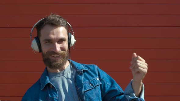 Happy Young Man with Headphones. Listening To Music and Dancing on a Red Background. Slow Motion