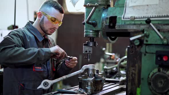 Worker in factory at machine. Worker in protective clothing in factory using machine