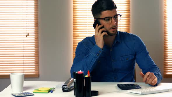 Male graphic designer talking on mobile phone