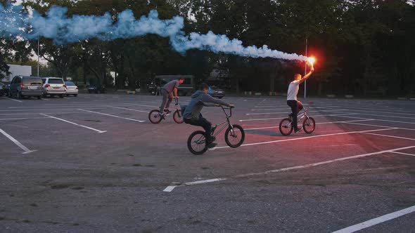 Young Athletic Men are Riding Bmx Bikes on Parking Lot and Performing Tricks One of Them is Holding