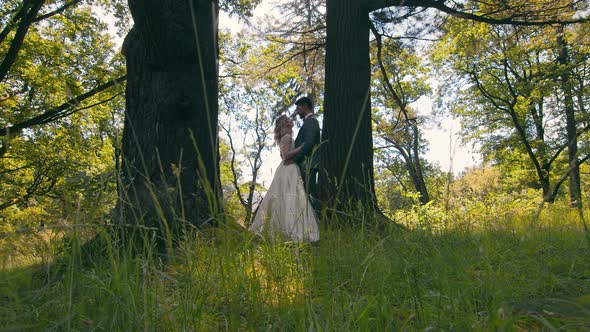 Young Couple Who Met in the Woods Near the Trees on a Background of Sunlight. The Newlyweds Gently
