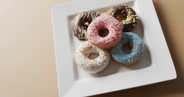 Video of donuts with icing on white plate over pink background