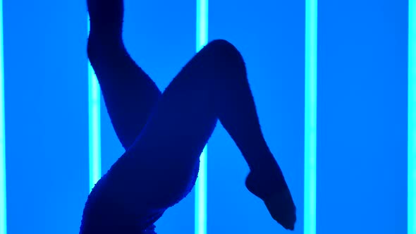 Young Woman Doing Gymnastic Exercises in the Studio Against the Background of Multicolored Neon