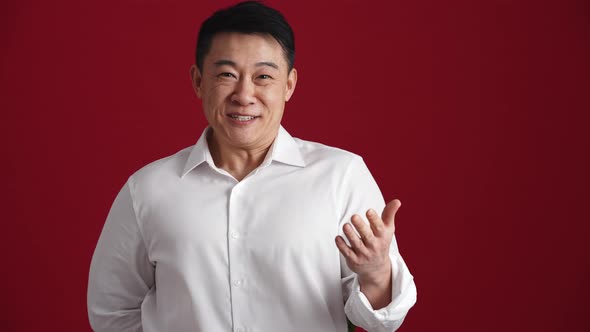 Happy Asian man in white shirt holds out a bouquet of red roses to the camera