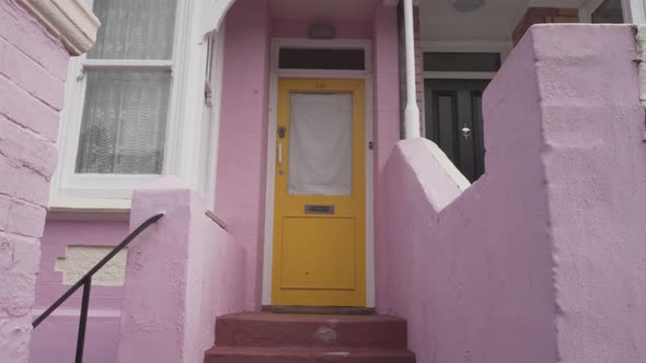 Young caucasian handsome man knocking the yellow door in a pink house entrance in brighton england u