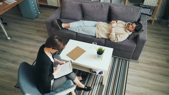 Male Teenager Speaking with Therapist During Individual Session in Office