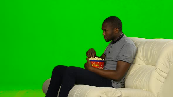 Man with Dark Skin Watching TV and Eating Popcorn. Green Screen