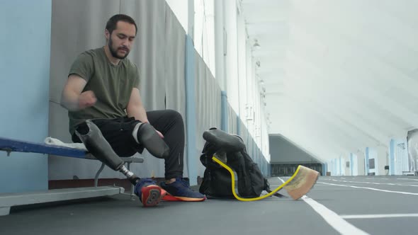 Sportsman Removing Prosthetic Leg and Sock after Training