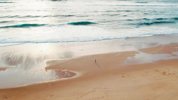 Girl Walks on Fine Sand Beach at Sunset