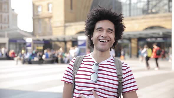 Man laughing in slow motion in front of busy train station