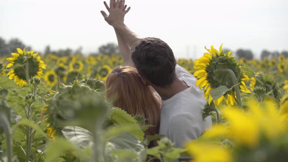 Back View of Happy Couple Holding Hands on the Sunflower Field