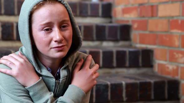 Sad schoolgirl sitting alone on staircase