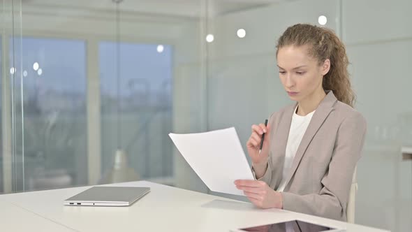 Hardworking Young Businesswoman Reading Documents in Office