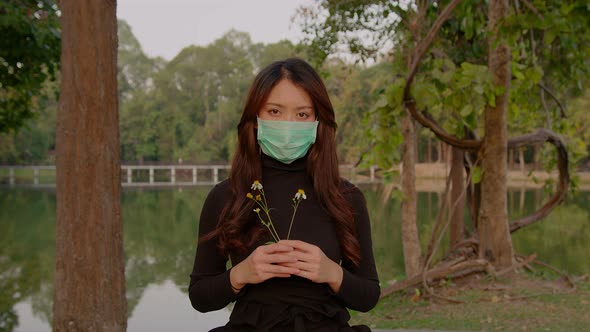 Thai Young Woman Slowly Looks Up Into the Camera in the Park at Sunset