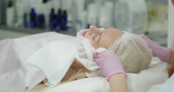 The Beautician Cleans The Skin With A Napkin After The Cosmetic Procedure. Beauty Clinic Concept