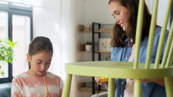 Mother and Daughter with Ruler Measuring Old Chair