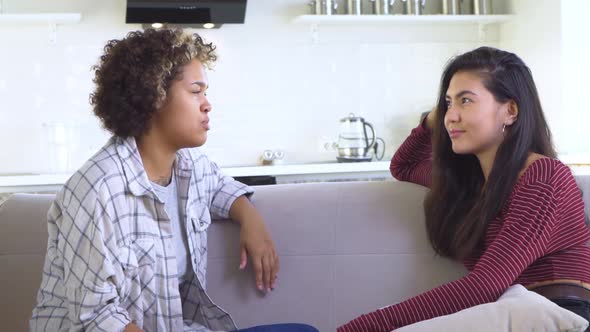 Two Girlfriends Gossiping While Sitting on the Couch