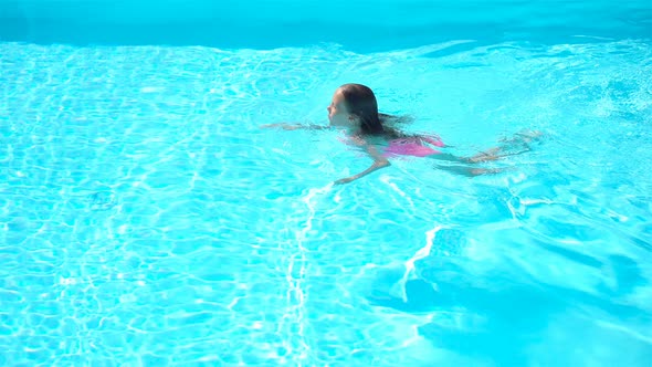 Adorable Little Girl Swimming at Outdoor Swimming Pool