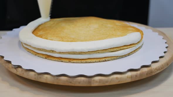 the Pastry Chef Squeezes the Cream Out of the Bag Onto the Sponge Cake