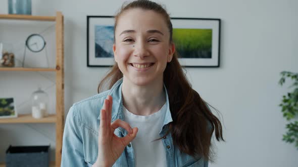 Cheerful Young Woman Showing Ok Hand Gesture Smiling Standing at Home Expressing Approval