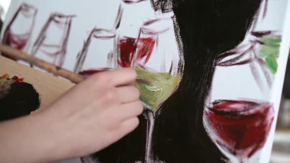 Close up of female hand painting on white canvas glass of wine and champagne