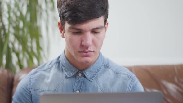 Young Man Sitting in Front of Laptop at Home