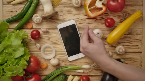 Faceless Woman Taking Smartphone From Table with Vegetables
