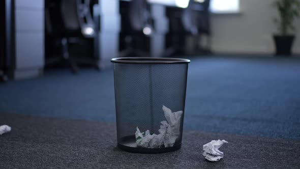 Closeup Office Trash Bin with Crumpled Paper Ball Falling Aside