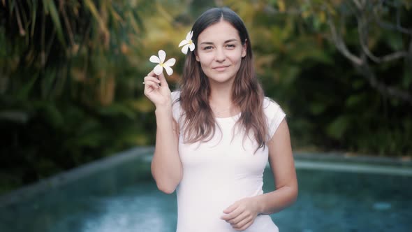 Brunette Lady Sniffs Plumeria Flower at Tropical Resort