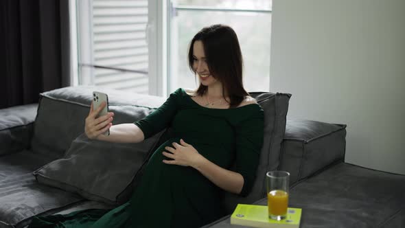 Pregnant Woman Video Chatting on Mobile Phone at Home